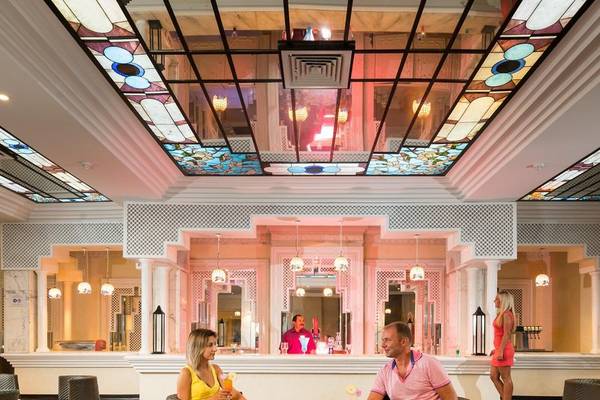 Hotellobby mit beleuchteten Decken und Sofas, wo ein Paar Getränke genießt.