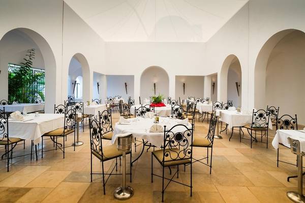 Restaurantsaal im Hotel Iliade Djerba by Magic Hotels mit weißen Tischen und Stühlen.