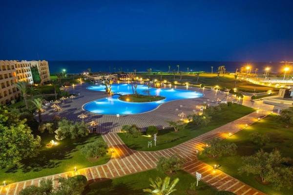 Abendansicht des Nour Palace Resort & Thalasso mit beleuchtetem Swimmingpool und Meer im Hintergrund.