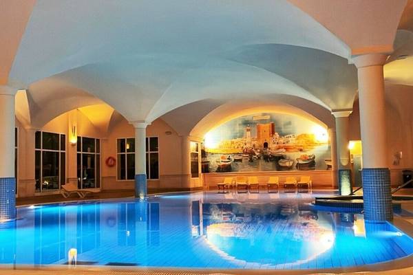 Innenpool des Nour Palace Resort & Thalasso mit blau beleuchtetem Wasser und Loungestühlen