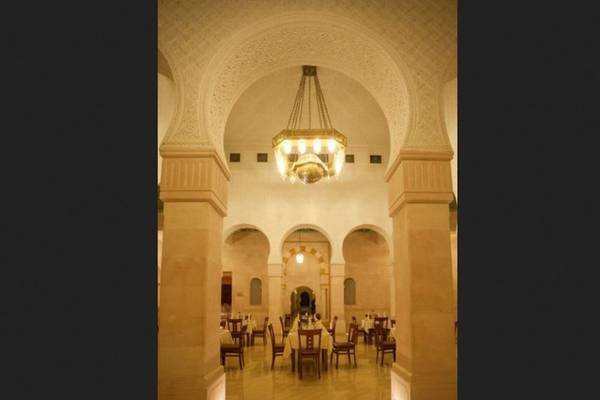 Innenansicht des Restaurants im Nour Palace Resort & Thalasso mit runden Bögen, Säulen und einer Deckenleuchte.
