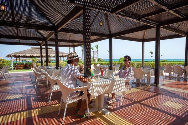 Terrasse im Nour Palace Resort & Thalasso mit zwei Gästen, die an einem Tisch sitzen und die Aussicht auf das Meer genießen.