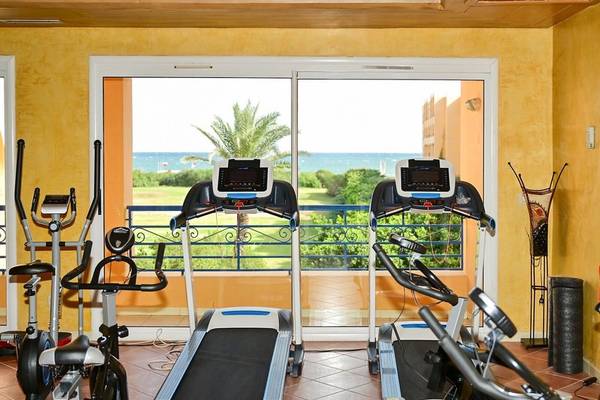 Fitnessraum mit mehreren Geräten und Blick auf das Meer