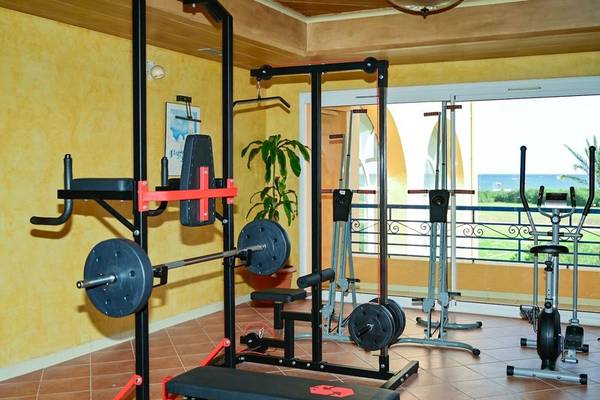 Fitnessraum im Nour Palace Resort & Thalasso mit Geräten und Blick auf das Meer.