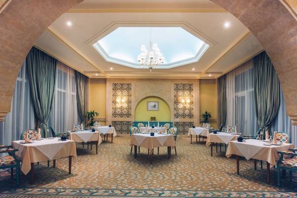 Speisesaal im Iberostar Waves Averroes Hotel mit runden Tischen und blauen Vorhängen.