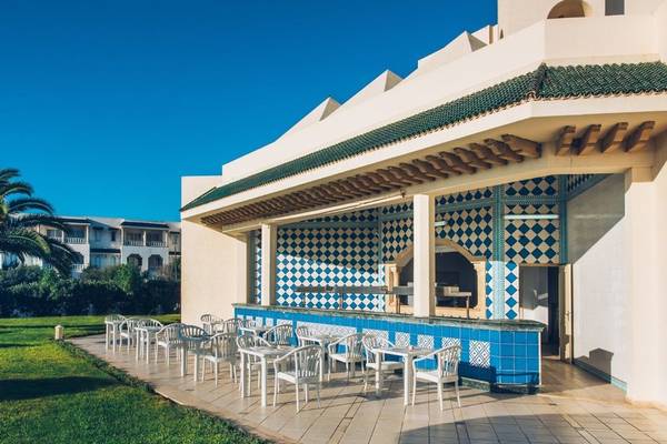 Außenterrasse des Iberostar Waves Averroes Hotels mit blauen und weißen Wandfliesen und weißen Tischen und Stühlen.