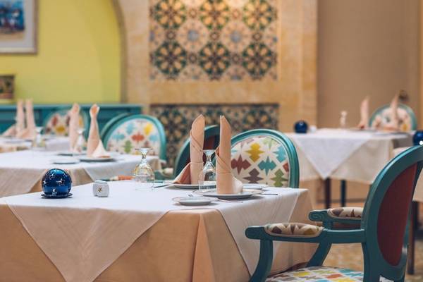 Speisesaal im Iberostar Waves Averroes Hotel mit gedeckten Tischen und bunten Stühlen.