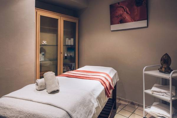 Behandlungsraum im Iberostar Waves Averroes Hotel mit Massageliege, Regal und Gemälde.