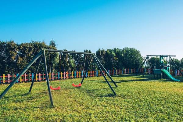 Kinderspielplatz im Hotel Iberostar Waves Averroes mit Schaukeln, Rutsche und buntem Zaun