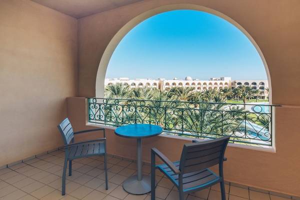 Balkon mit Tisch und Sitzen im Iberostar Waves Averroes Hotel, Blick auf Gebäude und Palmen