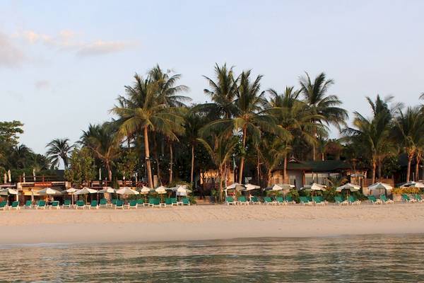 Strand des Banana Fan Sea Resorts mit Palmen, Sonnenliegen und Sonnenschirmen.