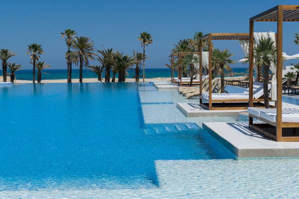 Außenpool des JAZ Tour Khalef Hotels mit Palmen und Blick auf den Strand