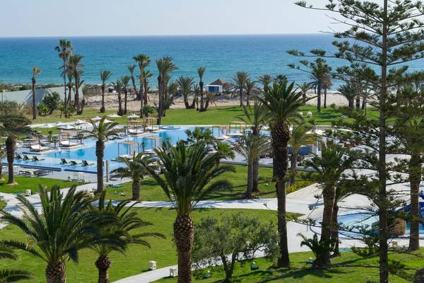 Außenbereich des JAZ Tour Khalef Hotels mit Swimmingpool und Palmen