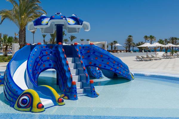 Wasserrutsche im Poolbereich des JAZ Tour Khalef Hotels mit bunten Farben und einem sommerlichen Hintergrund.