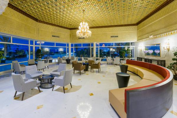 Lobby des JAZ Tour Khalef Hotels mit goldener Decke, Kronleuchter, Sofas und Tischen.