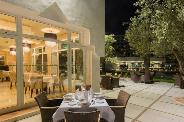 Außenbereich des JAZ Tour Khalef Hotels mit Tisch und Stühlen, bei Nacht.