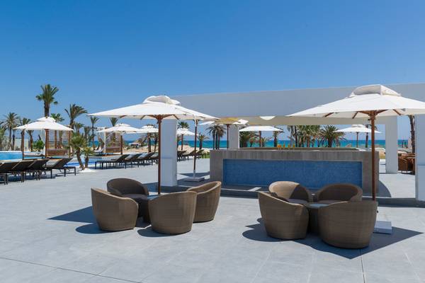 Außenbereich des JAZ Tour Khalef Hotels mit Pool, Sonnenliegen, Schirmen und Stühlen.