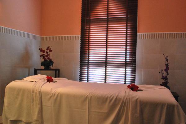 Massage-Behandlungsraum im JAZ Tour Khalef mit einem Massagetisch, weißen Laken, roten Rosen und geschlossenen Jalousien.