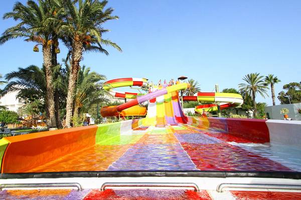 Farbige Wasserrutsche im Sahara Beach AquaPark Resort mit Palmen im Hintergrund.