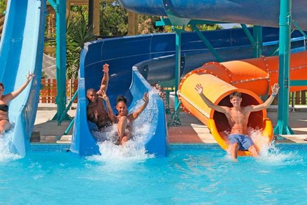 Gruppe von Menschen rutscht auf blauen und orangefarbenen Wasserrutschen im Sahara Beach AquaPark Resort.
