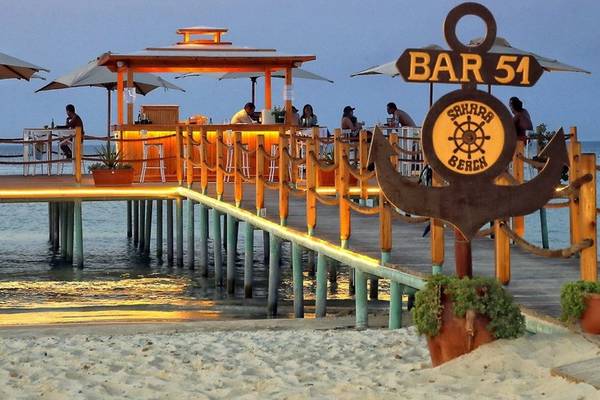 Abendansicht des Bars am Wasser im Sahara Beach AquaPark Resort mit Gästen und Palmen