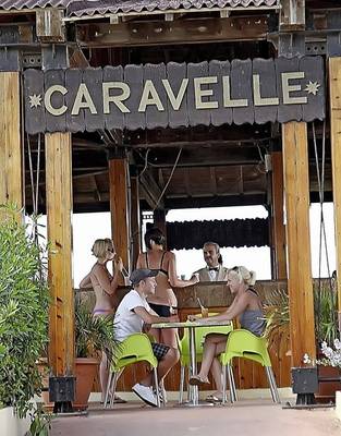 Gäste sitzen in grünen Stühlen vor der Bar Caravella im Sahara Beach AquaPark Resort.