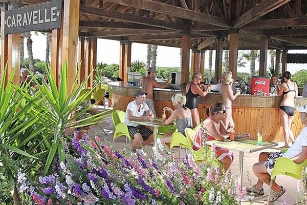 Gäste sitzen an Tischen auf der Terrasse des Caravelle im Sahara Beach AquaPark Resort.