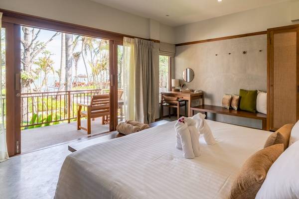 Innenansicht eines Hotelzimmers im Banana Fan Sea Resort mit einem großen Bett, Blick auf den Balkon und Meer