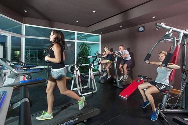 Fitnessstudio im Sahara Beach AquaPark Resort mit mehreren Personen, die auf Laufbändern und anderen Geräten trainieren.