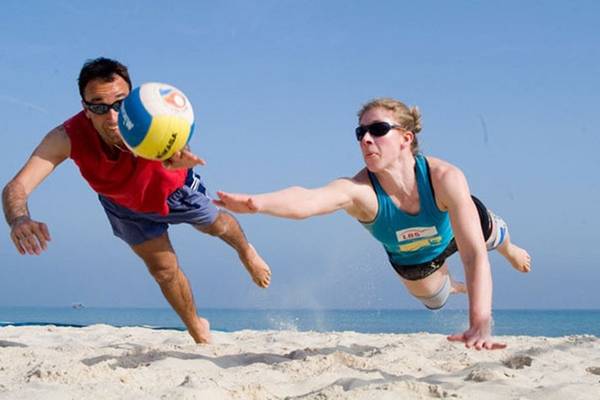 Ein Mann und eine Frau spielen Volleyball am Strand.
