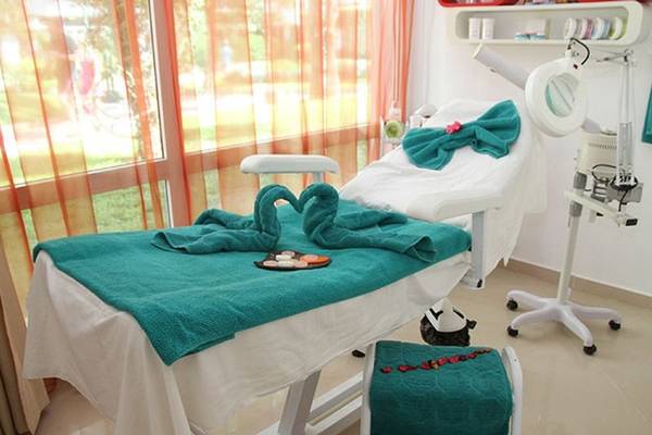 Behandlungszimmer im Sahara Beach AquaPark Resort mit grünen Handtüchern und Blick auf den Garten.