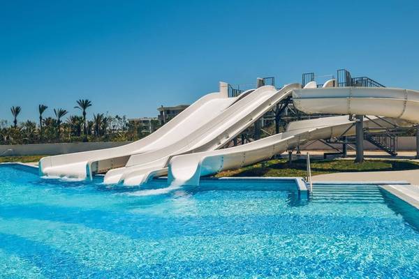 Wasserrutschen im Iberostar Selection Kuriat Palace Hotel mit blauem Pool und blauem Himmel.