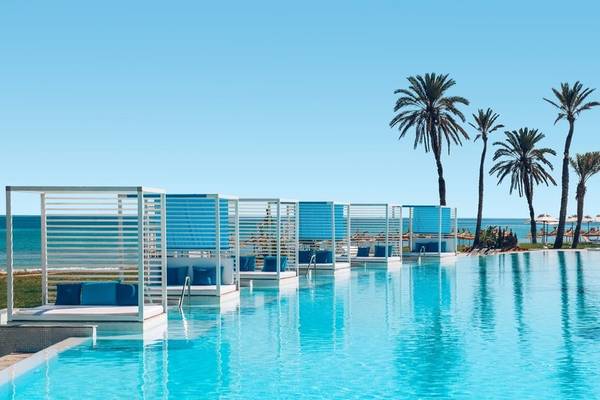 Ein blauer Pool mit Loungesesseln und Blick auf das Meer im Iberostar Selection Kuriat Palace.
