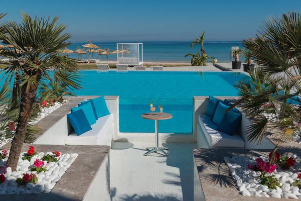 Außenpool des Iberostar Selection Kuriat Palace mit Blick auf das Meer und Palmen.