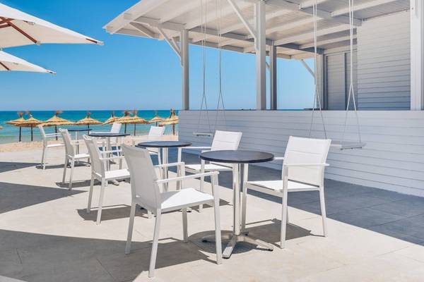 Außenbereich des Iberostar Selection Kuriat Palace Hotels mit weißen Tischen und Stühlen.