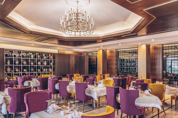 Innenbereich des Iberostar Selection Kuriat Palace Hotels mit einem runden Esstisch und einem großen Kronleuchter.