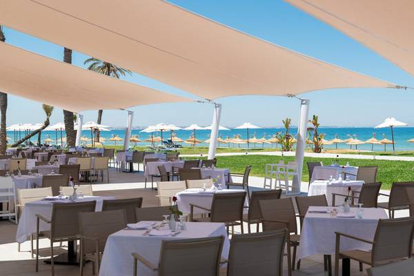 Außenbereich des Iberostar Selection Kuriat Palace Hotels mit großen Sonnensegeln und Tischen am Strand