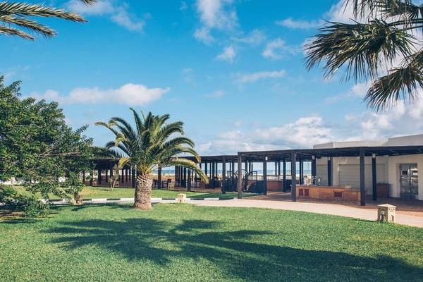 Außenbereich des Iberostar Selection Kantaoui Bay Hotels mit grünem Rasen und Palmen.