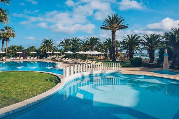 Außenpool des Iberostar Selection Kantaoui Bay Hotels mit Sonnenliegen und Palmen.