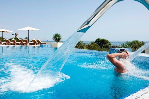 Mann, der sich unter dem Wasserfall im Pool des Iberostar Selection Kantaoui Bay erfrischt