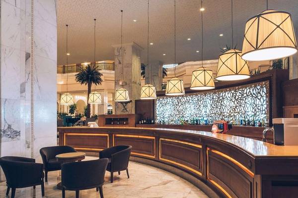 Hotellobby des Iberostar Selection Kantaoui Bay mit Bar, Sesseln und Kronleuchtern.