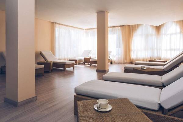 Loungebereich im Iberostar Selection Kantaoui Bay Hotel mit weißen Liegen und Holzboden.