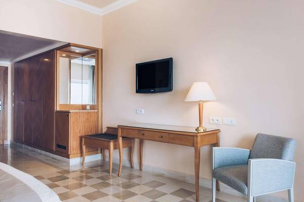 Innenansicht eines Hotelzimmers von Iberostar Selection Kantaoui Bay mit Bett, Schreibtisch, Stuhl und Fernseher.