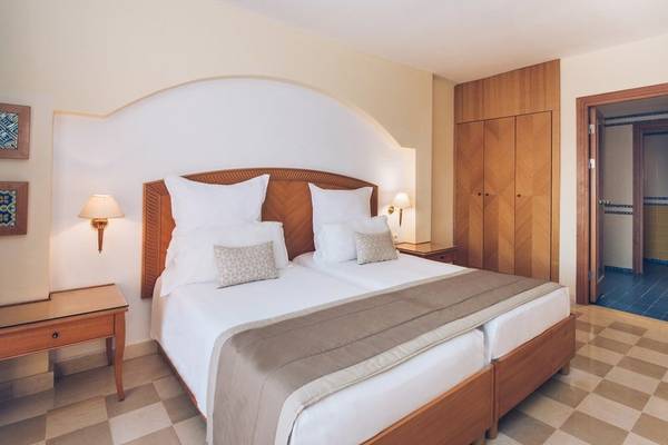 Doppelzimmer im Iberostar Selection Kantaoui Bay mit zwei Betten, weißen Kissen und blauen Bodenfliesen.