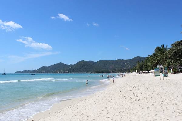 Strand des Banana Fan Sea Resorts mit weißen Sand, blauem Himmel und einigen Personen.