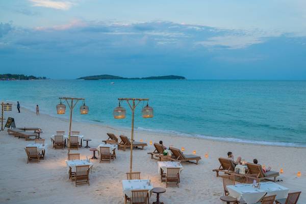 Strand des Banana Fan Sea Resort bei Sonnenuntergang mit Sonnenschirmen und Liegen am Meer