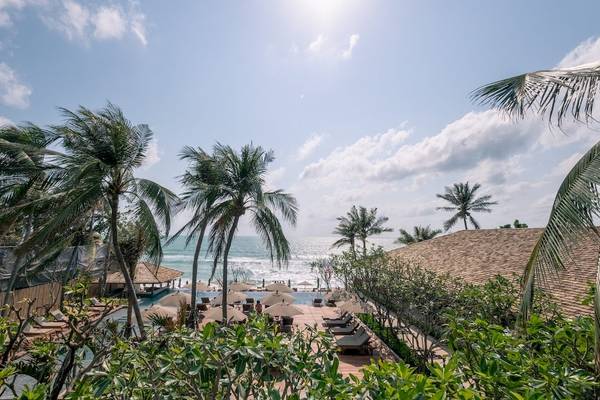 Aussicht auf den Strand des Banana Fan Sea Resorts mit Palmen und Sonnenliegen.