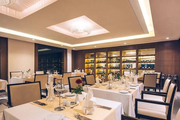 Innenansicht des Restaurants im Iberostar Selection Diar El Andalous Hotel mit gedeckten Tischen und dekorierten Flaschen im Hintergrund.