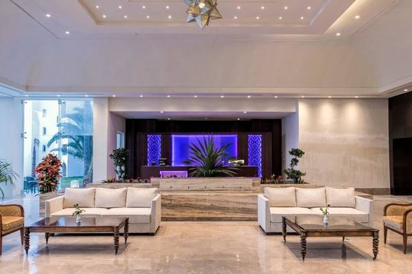 Hotelfoyer mit Sitzbereich, Empfangstresen und dekorativen Pflanzen.