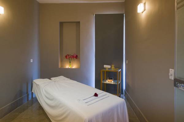 Massageraum im Iberostar Selection Diar El Andalous Hotel mit einem Massagetisch, einer Tischlampe und einem Blumenstrauß.
